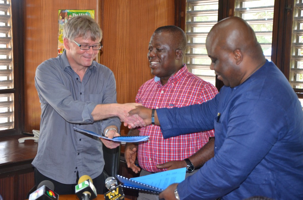 Niels Vestergaard receives copy of agreement from Health minister whiles the deputy social minister looks on.